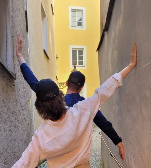 Zwei Spielende mit ausgebreiteten Armen in einer engen Passauer Gasse